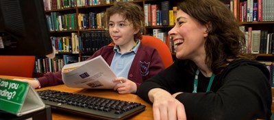 Librarian demonstrating coding to a school pupil during a Code Club session at Kirkaldy Library in Fife. 